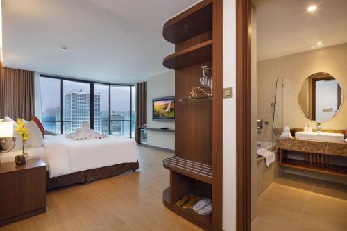 a bedroom with a bed and a bathroom with a sink at Regalia Gold Hotel in Nha Trang