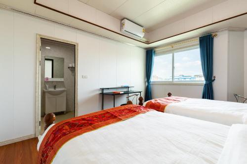 twee bedden in een kamer met een raam bij Sukhumvit 101 HOTEL in Bangkok