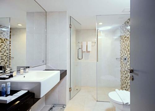 a white bathroom with a sink and a shower at CROWN PRINCE Hotel Surabaya Managed by Midtown Indonesia in Surabaya