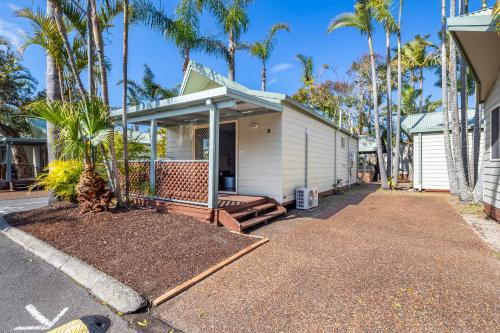 a house with a porch with palm trees at Ingenia Holidays One Mile Beach in One Mile
