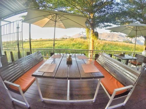 a wooden table with two chairs and an umbrella at The Vista Pool Villa in Kanchanaburi