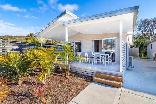 a home with a wrap around deck with a table and chairs at Ingenia Holidays One Mile Beach in One Mile