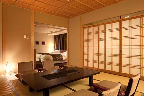a room with a table and chairs and a bedroom at Yumoto Konpira Onsen Hananoyu Kobaitei in Kotohira