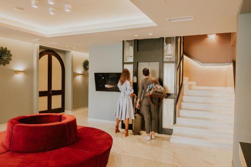 a man and woman standing in a lobby looking at a painting at Pefkaki Boutique Hotel Loutraki in Loutraki