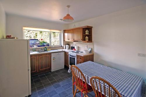 cocina con mesa y sillas y cocina con fregadero en Cottage at Youghal Bridge, en DʼLoughtane Cross Roads