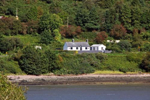 a house on a hill next to a body of water at Cottage at Youghal Bridge in DʼLoughtane Cross Roads