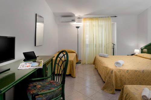 a hotel room with two beds and a desk with a computer at Hotel Villaggio Stromboli in Santa Domenica