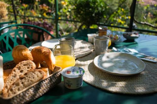 einen Tisch mit einem Korb Brot und einem Teller Orangensaft in der Unterkunft Hôtel de la Béroche in Saint Aubin Sauges