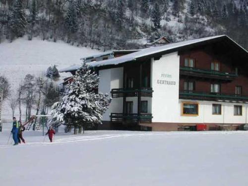 a ski lodge with people standing outside of it in the snow at Pension Gertraud in Bad Kleinkirchheim