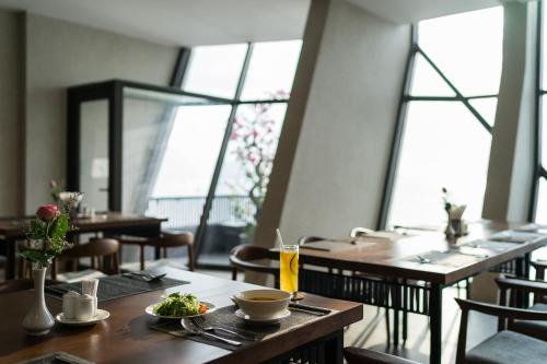ein Restaurant mit Holztischen und -stühlen und Fenstern in der Unterkunft Joy Trip Hotel & Spa Nha Trang in Nha Trang