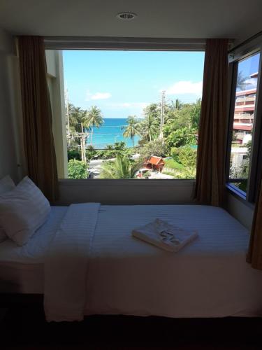 a bedroom with a large window with a view of the ocean at PorterHouse Beach Hotel in Patong Beach