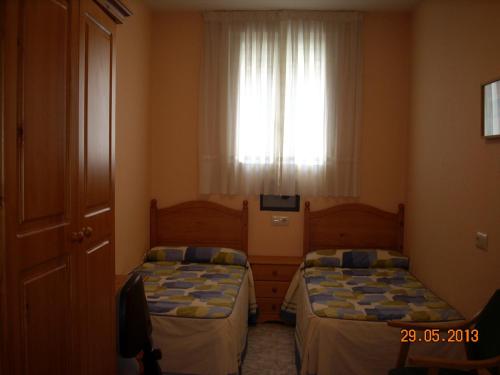 two beds in a small room with a window at Hostal Vadama in Segovia