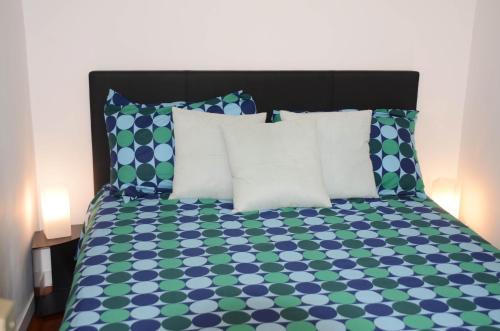 - un lit avec des draps et des oreillers bleus et verts dans l'établissement Calme et Cosy appart proche plage quartier port, à Nice