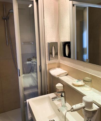 a bathroom with a sink and a mirror and a shower at City Hotel Ost am Kö in Augsburg