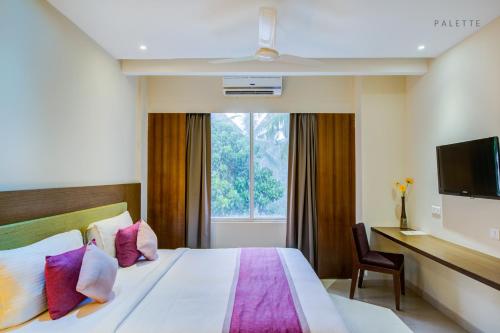 a hotel room with a bed and a desk and a window at JK Residency Kelakam in Kelakam