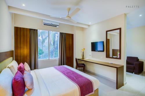 a hotel room with a bed and a desk and a mirror at JK Residency Kelakam in Kelakam