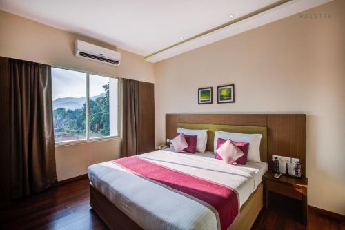 a bedroom with a large bed with a window at JK Residency Kelakam in Kelakam