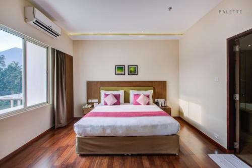 a bedroom with a large bed with pink pillows at JK Residency Kelakam in Kelakam