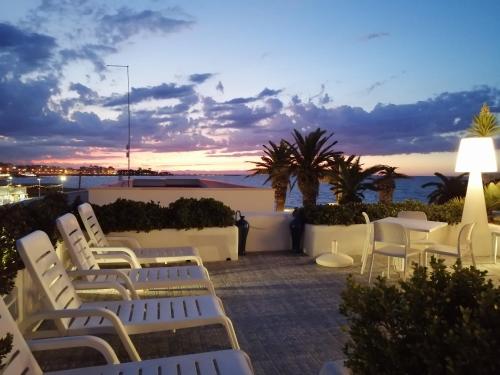 a patio with white chairs and the ocean at sunset at La Bella Trani - Suites and B&B in Trani