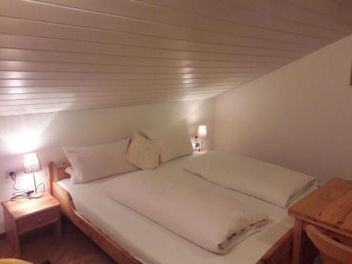 a bedroom with a large white bed with two lamps at Haus Frank Pitztal in Sankt Leonhard im Pitztal