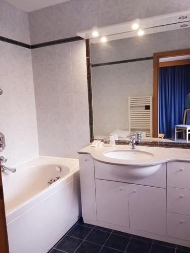 y baño con lavabo, bañera y espejo. en Residenza e Appartamenti Le Colonnine en Pozza di Fassa