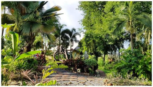 a garden with palm trees and a stone path at Baan Sakuna Hotel in Chiang Khong