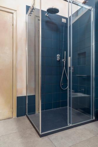 a glass shower in a bathroom with blue tiles at Boutique Apartment Urbino in Urbino