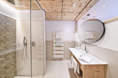 bagno con doccia, lavandino e specchio di Hotel Ortler a Tirolo