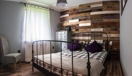 a bedroom with a bed with a wooden accent wall at Apartamenty Tabula in Duszniki Zdrój