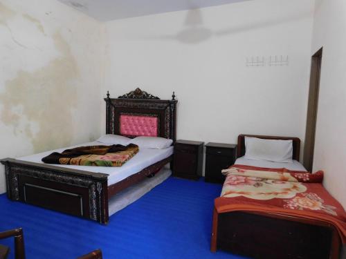 2 camas en una habitación con suelo azul en Hamaliya Hotel & Restaurant en Bālākot