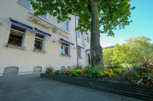 a building with a tree and flowers in front of it at Budget by Hotel Savoy Hannover in Hannover