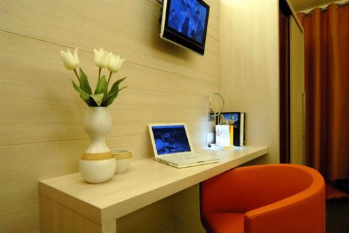a desk with a vase of flowers and a laptop at Hotel Parco Dei Principi in Grottammare