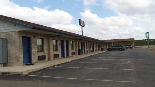 a car parked in a parking lot next to a building at Sona Inn in Dilley