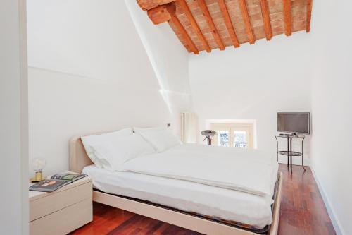 Cama en habitación con paredes blancas y suelo de madera. en Ex Tribunale Palazzo Bentivoglio Apartment, en Ferrara