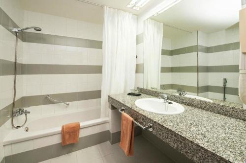 a bathroom with a sink and a tub and a mirror at Relaxia Olivina in Puerto del Carmen