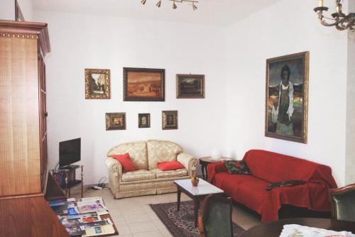 a living room with a red couch and pictures on the wall at LE GINESTRE in Sulmona