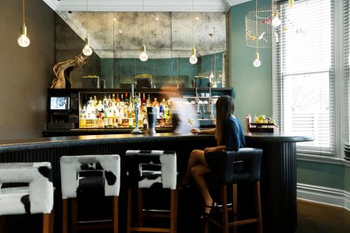 a woman sitting at a bar in a restaurant at The Lodge Hotel - Putney in London