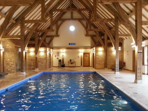 a large swimming pool in a building with wooden beams at Carnoustie Lodge in Wisbech