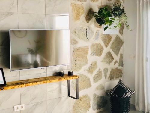 a living room with a tv on a stone wall at Canaryislandshost l Nazaret Suites in Nazaret