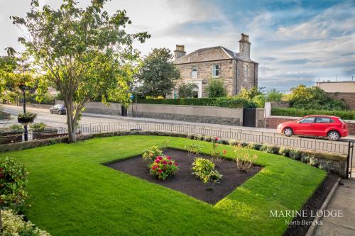 un jardin en face d'une maison avec une voiture rouge dans l'établissement "Fraser's" at Marine Lodge, à North Berwick