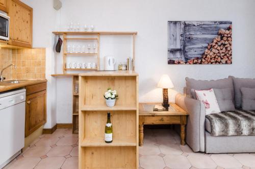 - un salon avec un canapé et une table avec une bouteille de vin dans l'établissement Appartement Le Chamois, à Megève