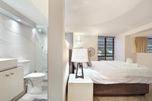 a white bedroom with a bed and a bathroom at G Zero 3 @ The Breakers in Hout Bay
