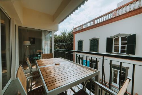 a balcony with a wooden table and chairs at City Garden by Madeira Best Apartments in Funchal