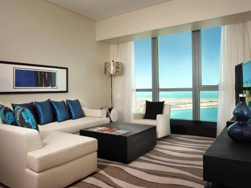 a living room with a white couch and blue pillows at Sofitel Abu Dhabi Corniche in Abu Dhabi