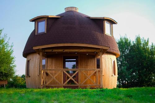 a small round house with a roof on a field at Grzybek Maison champignon in Kętrzyn