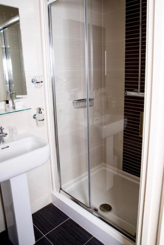 a shower with a glass door next to a sink at Gwesty'r Emlyn Hotel in Newcastle Emlyn