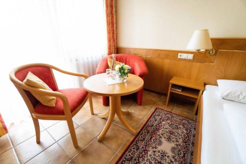 a hotel room with a table and chairs and a bed at Gasthaus zum Rössel Lichtenau in Scherzheim