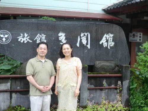 a man and a woman standing in front of a sign at Tamonkan in Tsuruoka