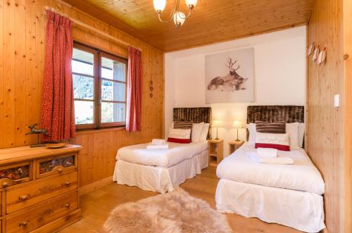 two beds in a room with wood paneled walls at Les Clochettes in Megève