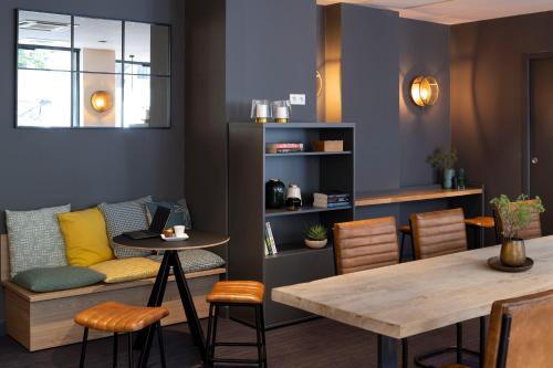 a dining room with a table and a couch at Aparthotel 37 Lodge Courbevoie Paris La Défense in Courbevoie